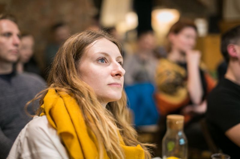 A woman in a yellow scarf listening closely from the audience